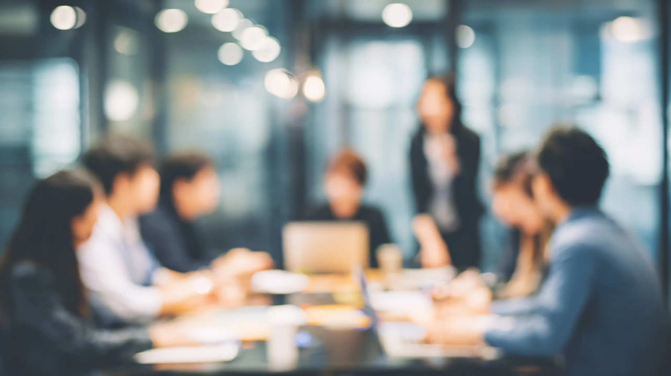 Blurry business team meeting discussing ideas in modern office conference room