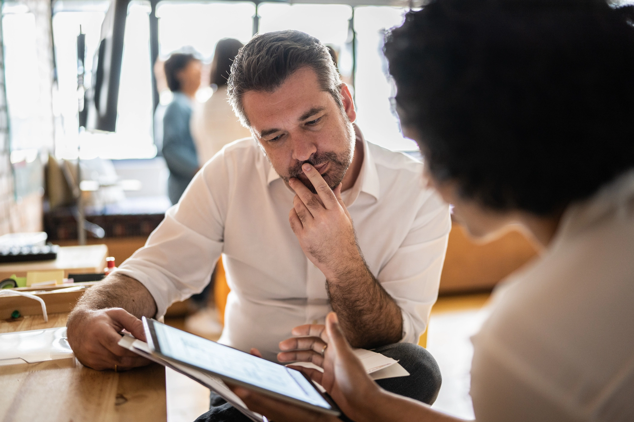 Man and woman sitting at desk viewing an ipad in an office environment